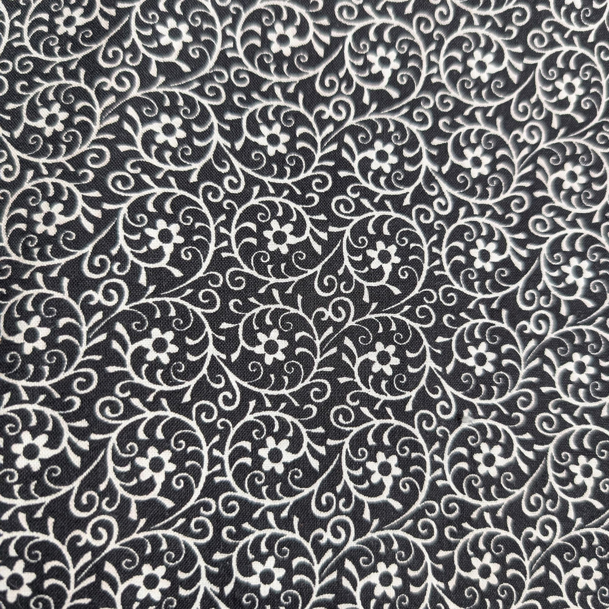 Close-up of the Black Floral Welding Cap fabric showing white floral and vine patterns on black cotton — handcrafted by HD Welding Hats.