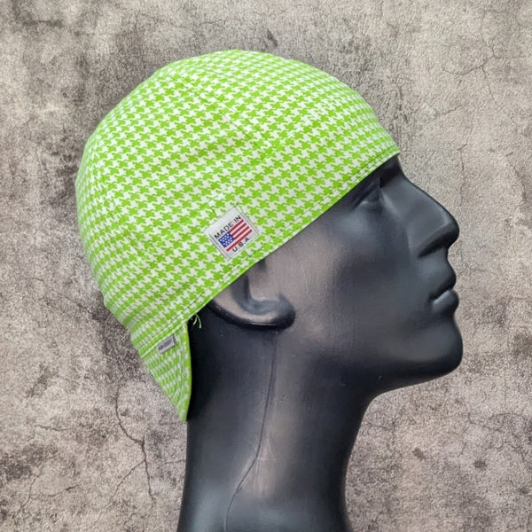 Lime green and white houndstooth welding cap with Made in USA tag, displayed on black mannequin against gray textured background.