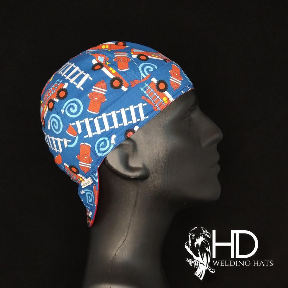 Fire Truck Welding Cap featuring red fire trucks, hydrants, and ladders on a blue cotton background, handcrafted by HD Welding Hats with FR denim brim.