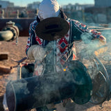 Person welding with protective gear in an industrial setting