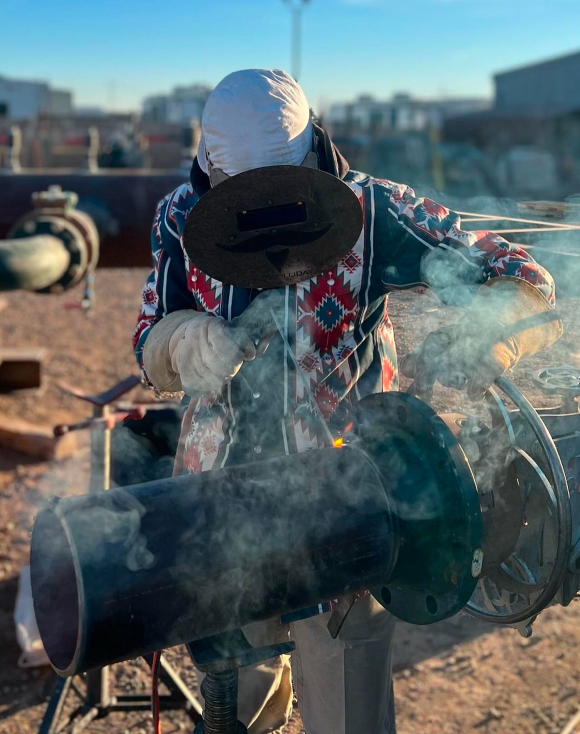 Person welding with protective gear in an industrial setting