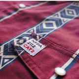 Close-up of a red shirt with geometric patterns and a label on the collar.