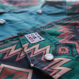 Close-up of a green patterned shirt with a label on a blurred background
