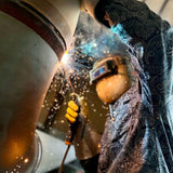 Person welding metal with protective gear in a workshop setting