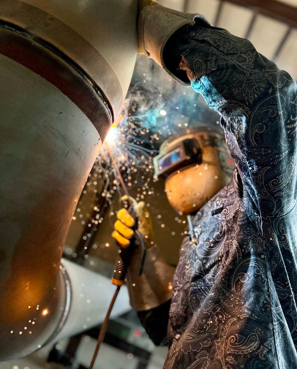 Person welding metal with protective gear in a workshop setting