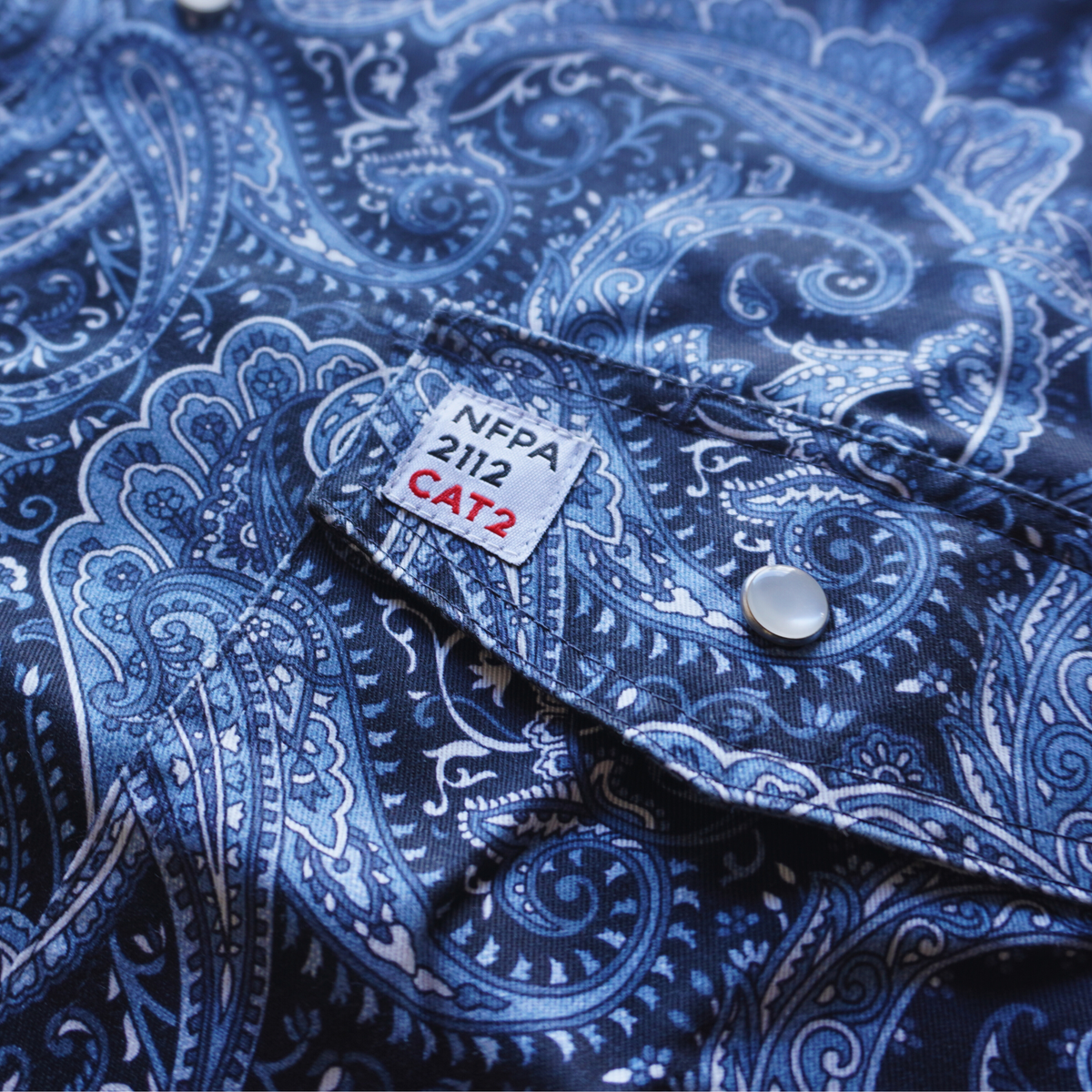 Blue paisley patterned shirt with NFPA 2112 CAT2 label on collar