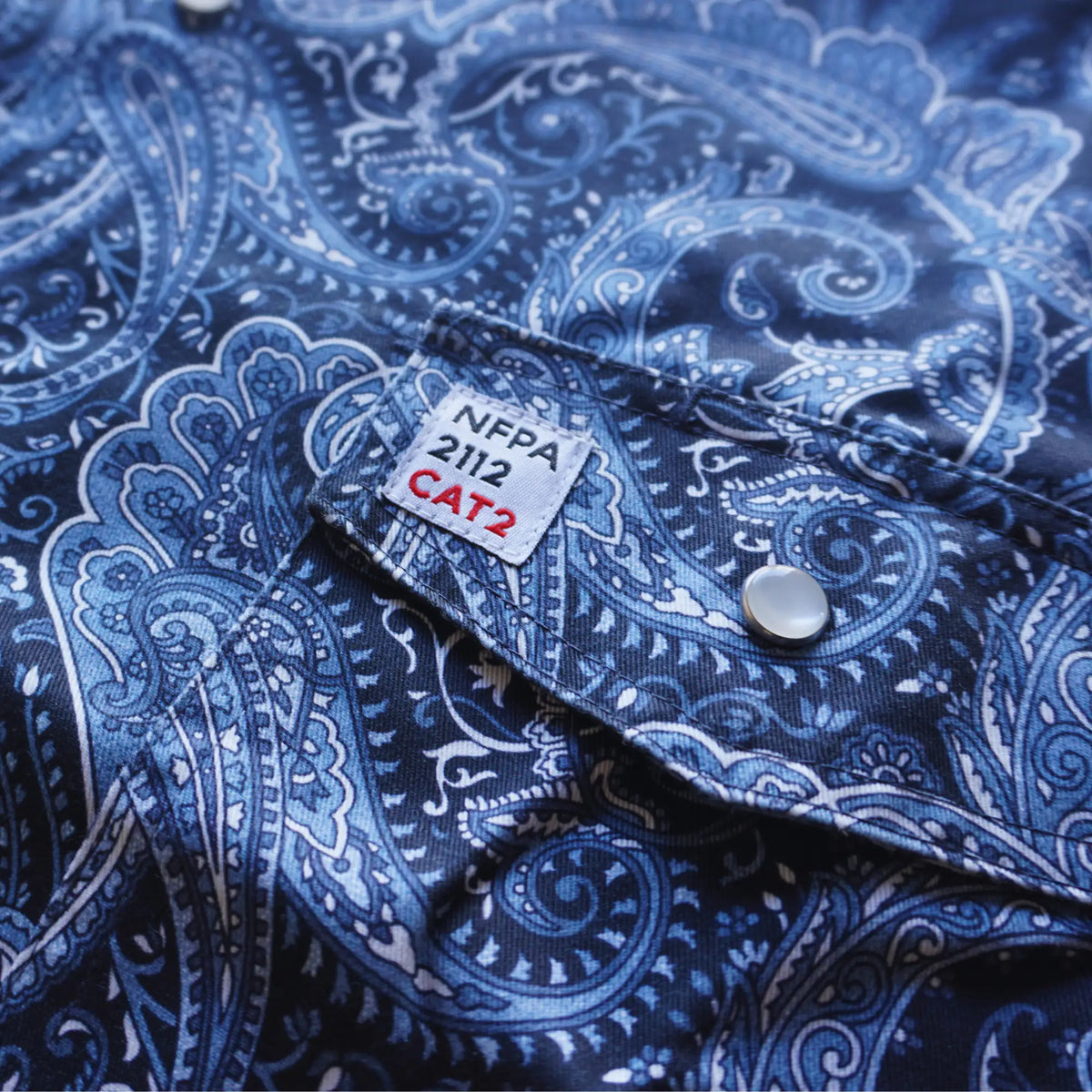Blue paisley patterned shirt with NFPA 2112 CAT2 label on collar