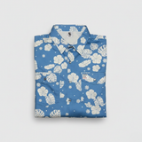 Folded blue shirt with white floral pattern on a light gray background