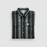 A folded black long-sleeve button-up shirt with white vertical stripes and geometric diamond patterns, displayed on a light gray background.
