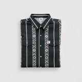 A folded black long-sleeve button-up shirt with white vertical stripes and geometric diamond patterns, displayed on a light gray background.