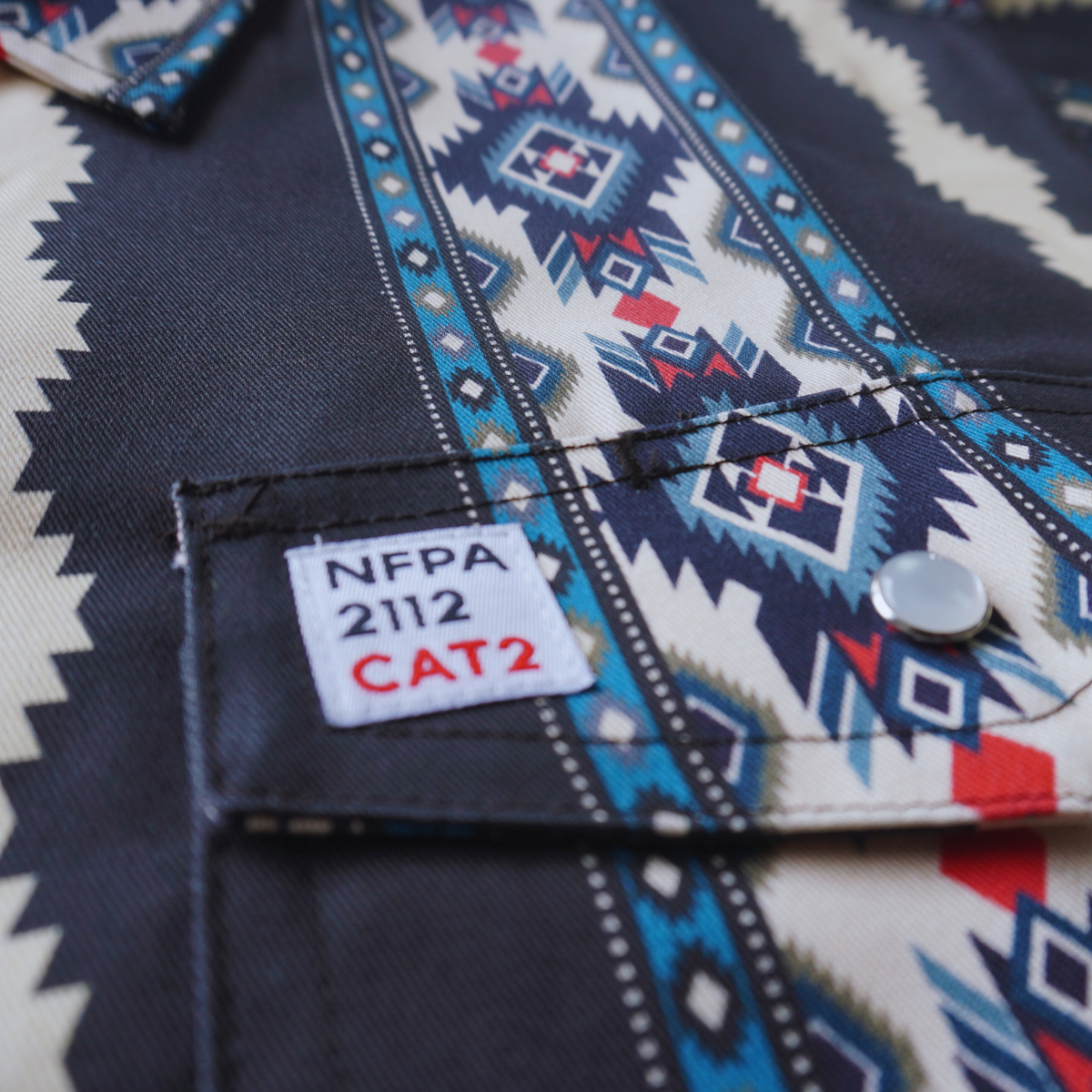Close-up of the Rattler patterned fabric with an NFPA 2112 CAT2 label.